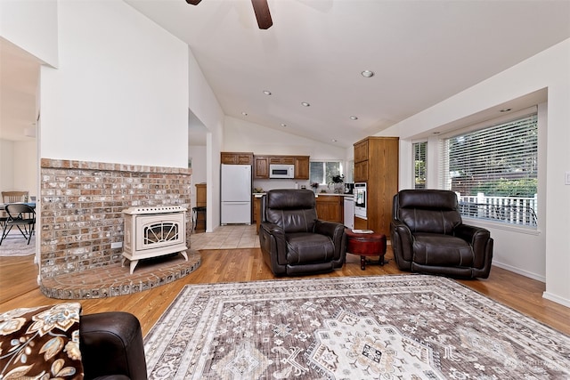 living room with ceiling fan, vaulted ceiling, and light hardwood / wood-style floors