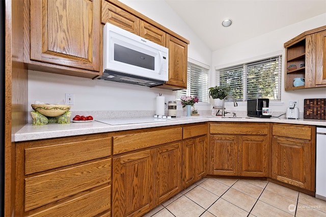 kitchen with light tile patterned floors, vaulted ceiling, sink, and white appliances