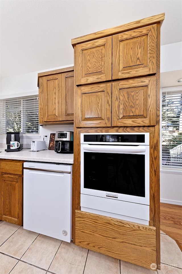 kitchen with white appliances, light tile patterned floors, and plenty of natural light