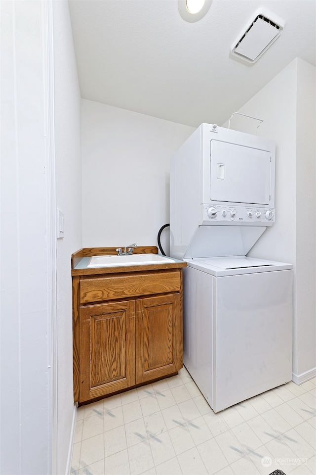 laundry room with cabinets, sink, and stacked washer and dryer