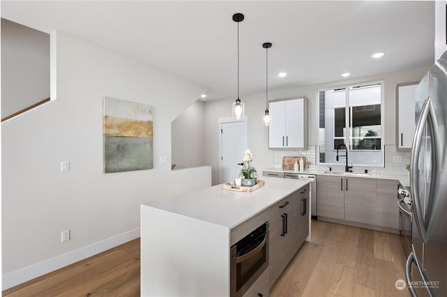 kitchen with sink, hanging light fixtures, a center island, and light hardwood / wood-style flooring