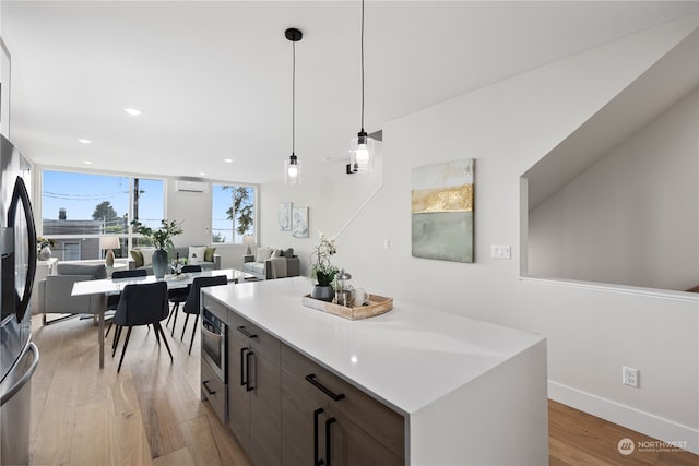 kitchen with a kitchen island, light hardwood / wood-style flooring, dark brown cabinets, hanging light fixtures, and an AC wall unit