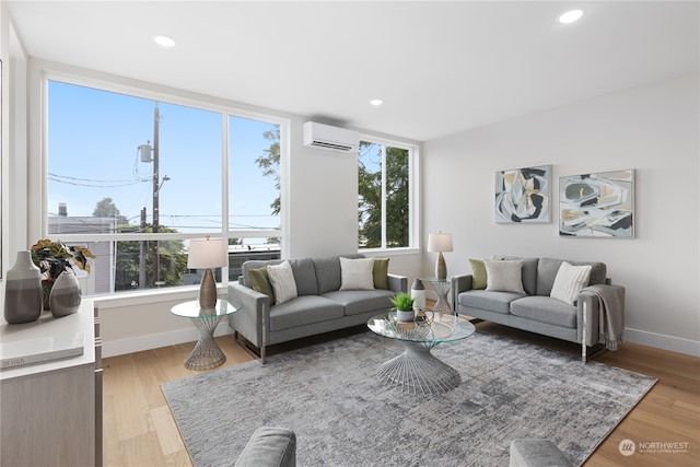 living room featuring an AC wall unit, a healthy amount of sunlight, and light hardwood / wood-style flooring