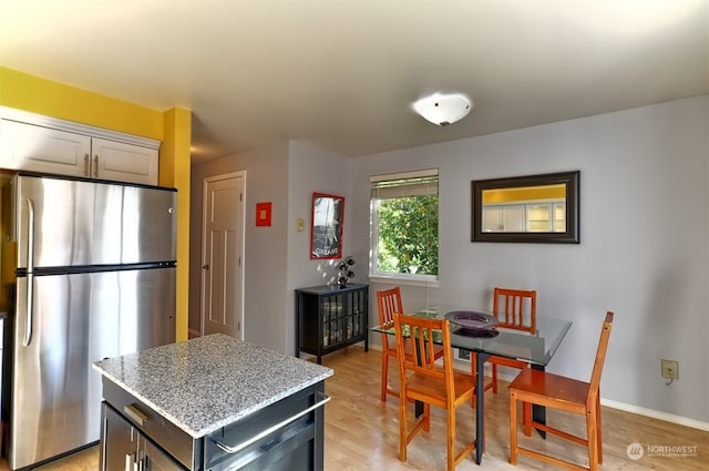 kitchen featuring a center island, stainless steel fridge, light stone countertops, and light wood-type flooring