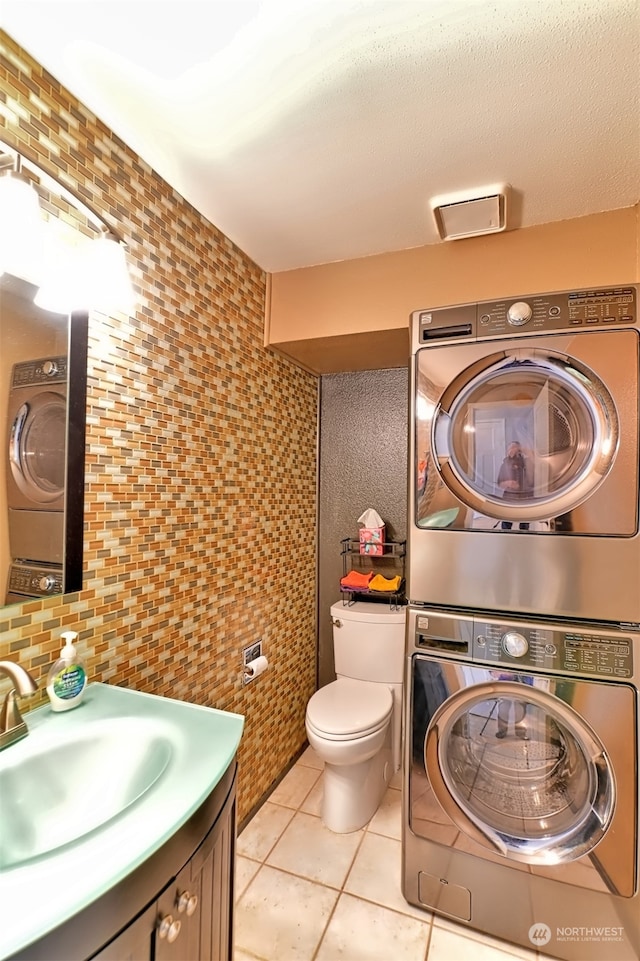 bathroom with vanity, tile patterned floors, stacked washer and dryer, decorative backsplash, and toilet