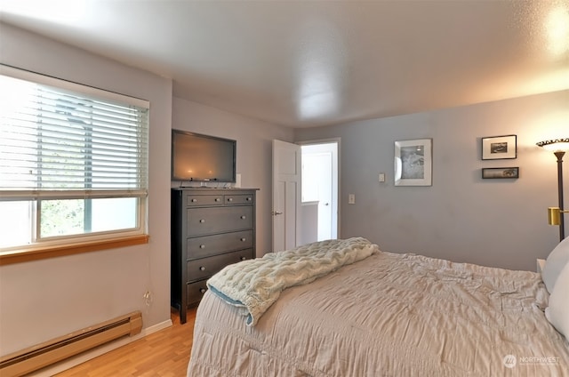 bedroom with light hardwood / wood-style flooring and a baseboard radiator