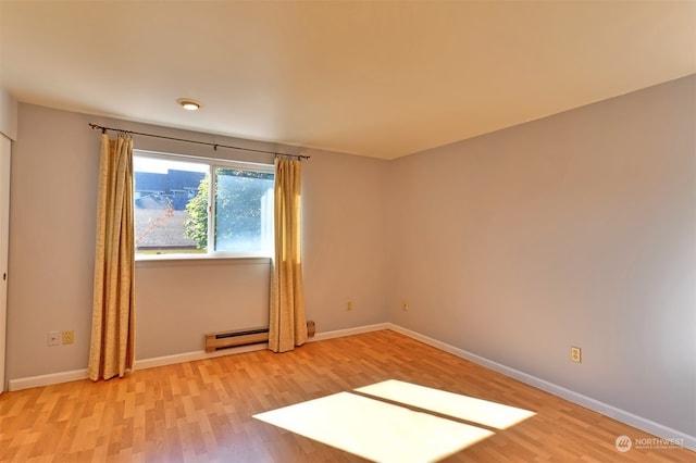 spare room with a baseboard radiator and light hardwood / wood-style flooring