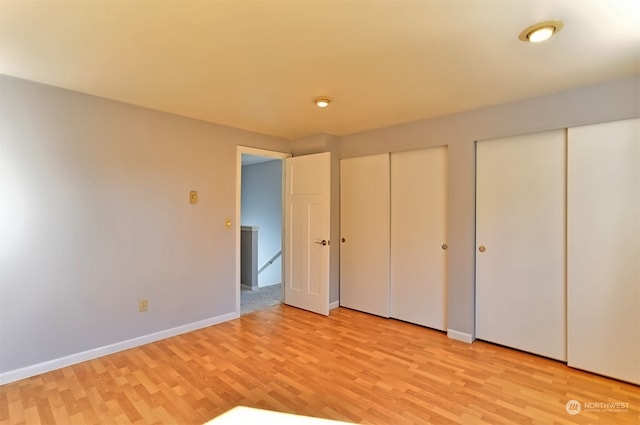 unfurnished bedroom featuring light wood-type flooring and two closets