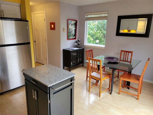 kitchen with stainless steel fridge, light hardwood / wood-style flooring, and light stone counters