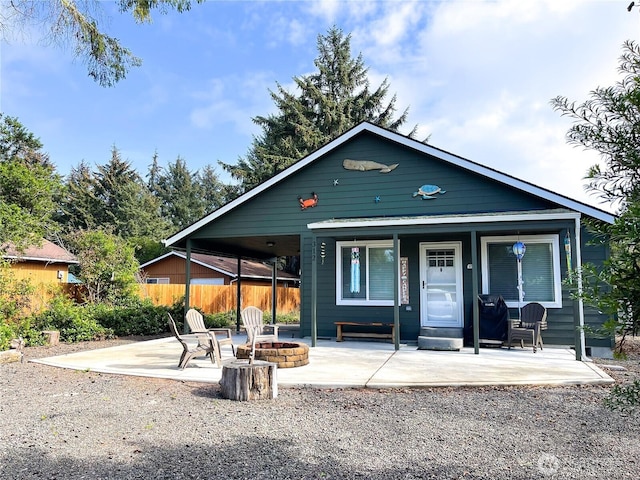 view of front of home with a patio area, a fire pit, and fence