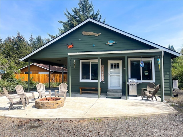 view of front facade with fence, a fire pit, covered porch, and central air condition unit