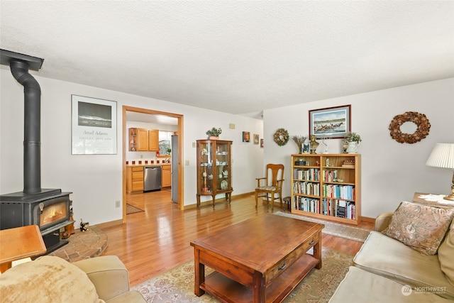 living room featuring a textured ceiling, light wood-type flooring, and a wood stove