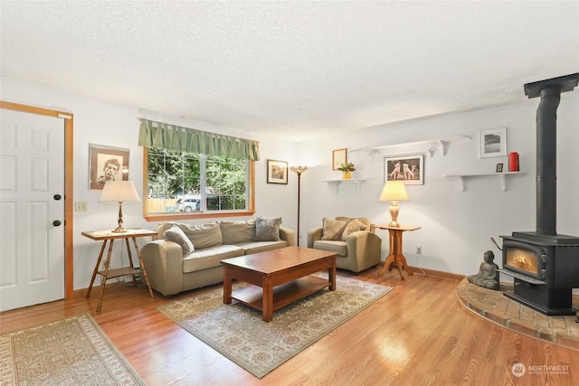 7220 Fair Oaks Loop SE, Olympia, WA 98513 - living room featuring a wood stove, a textured ceiling, light wood finished floors, and baseboards