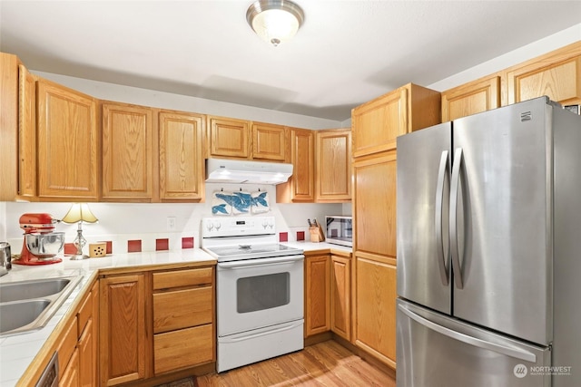 7220 Fair Oaks Loop SE, Olympia, WA 98513 - kitchen with stainless steel appliances, under cabinet range hood, tile counters, a sink, and light wood-style flooring