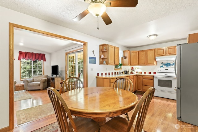 dining room featuring ceiling fan, light hardwood / wood-style floors, sink, a textured ceiling, and vaulted ceiling