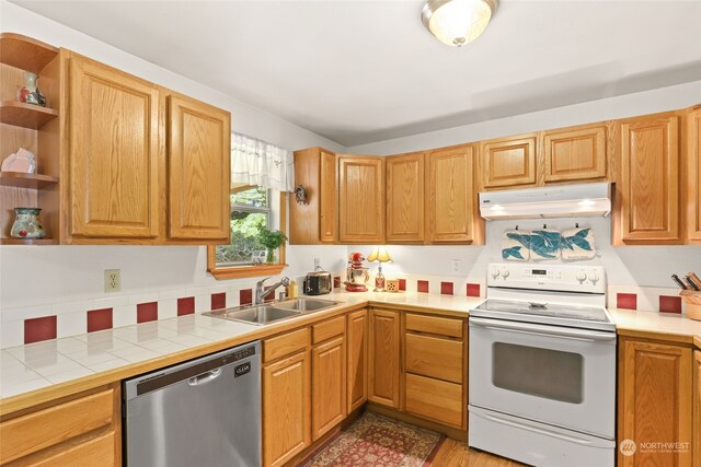 kitchen featuring sink, white electric range, light hardwood / wood-style flooring, tile countertops, and dishwasher