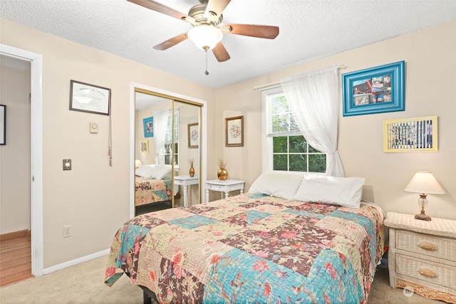 carpeted bedroom with ceiling fan, a textured ceiling, and a closet