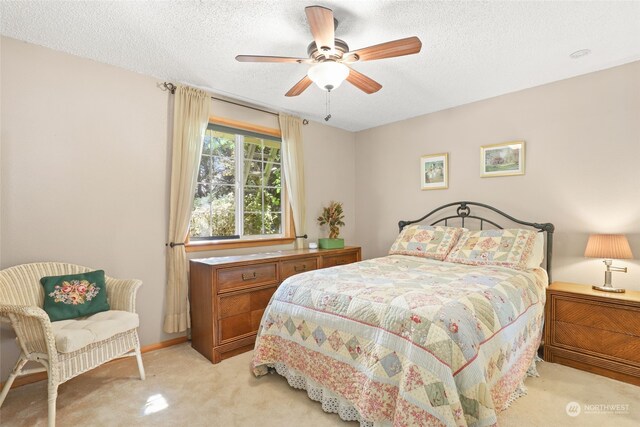 carpeted bedroom featuring ceiling fan and a textured ceiling