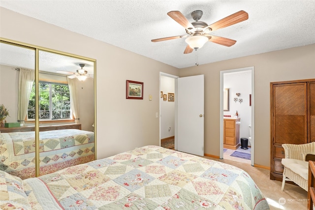 carpeted bedroom featuring ceiling fan, a textured ceiling, a closet, and ensuite bath