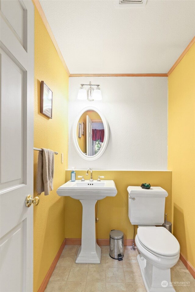 bathroom with crown molding, tile patterned flooring, and toilet