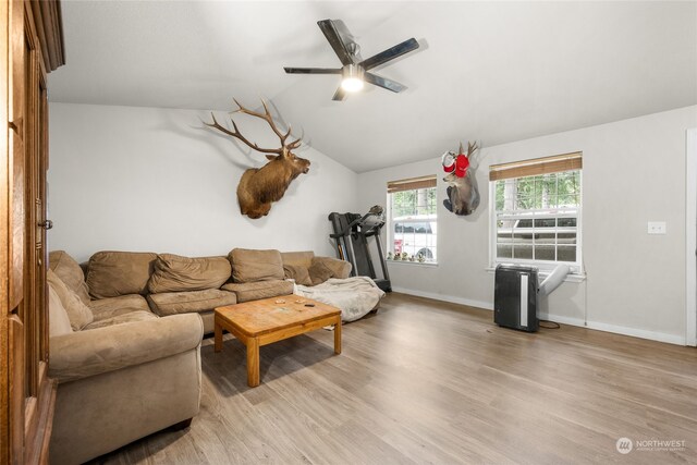 living room with ceiling fan, light hardwood / wood-style floors, and vaulted ceiling