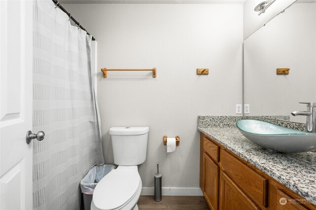 bathroom with hardwood / wood-style flooring, vanity, walk in shower, and toilet