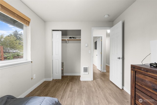 bedroom featuring heating unit, a closet, and light hardwood / wood-style floors