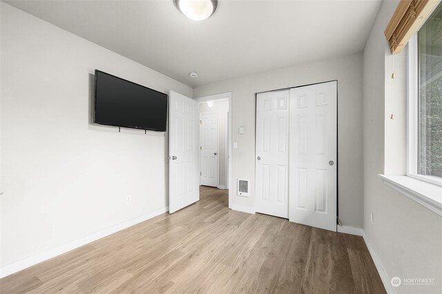 unfurnished bedroom featuring light wood-type flooring and a closet