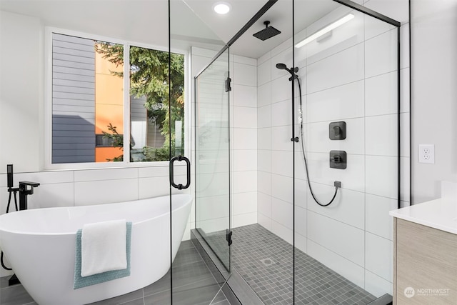 bathroom featuring shower with separate bathtub, tile patterned floors, vanity, and tile walls