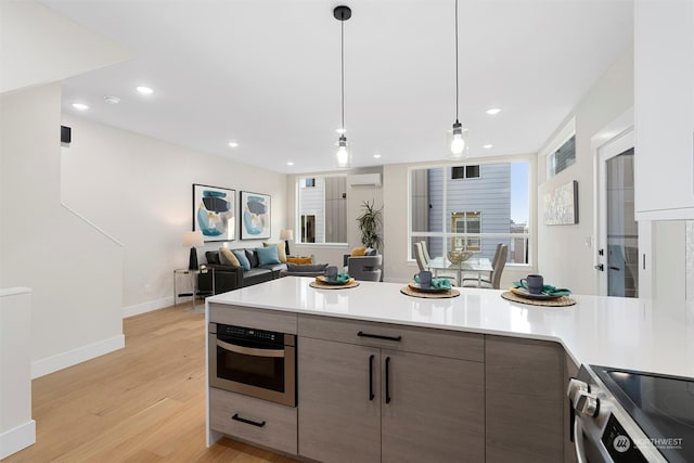 kitchen featuring pendant lighting, light hardwood / wood-style flooring, dark brown cabinets, a wall mounted AC, and appliances with stainless steel finishes