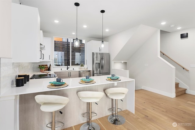 kitchen with light hardwood / wood-style flooring, decorative light fixtures, sink, stainless steel appliances, and white cabinetry