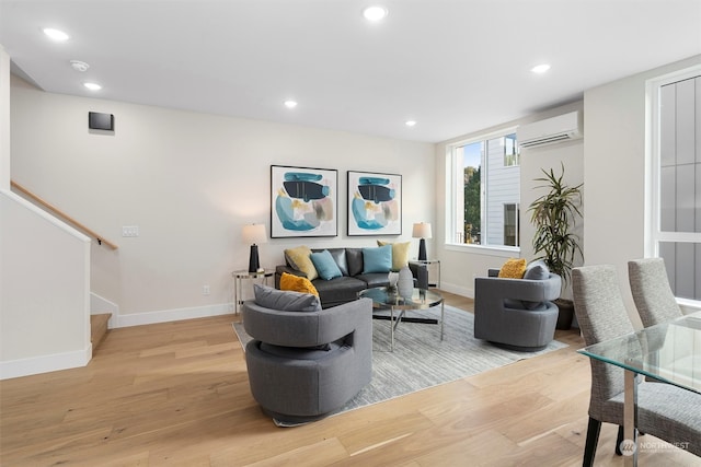 living room with a wall mounted air conditioner and light hardwood / wood-style floors