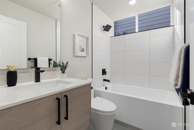 full bathroom featuring tiled shower / bath, vanity, and toilet