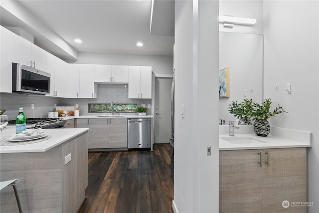 kitchen featuring dark wood-type flooring, white cabinets, stainless steel appliances, and sink