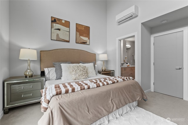 bedroom with ensuite bathroom, an AC wall unit, and light colored carpet