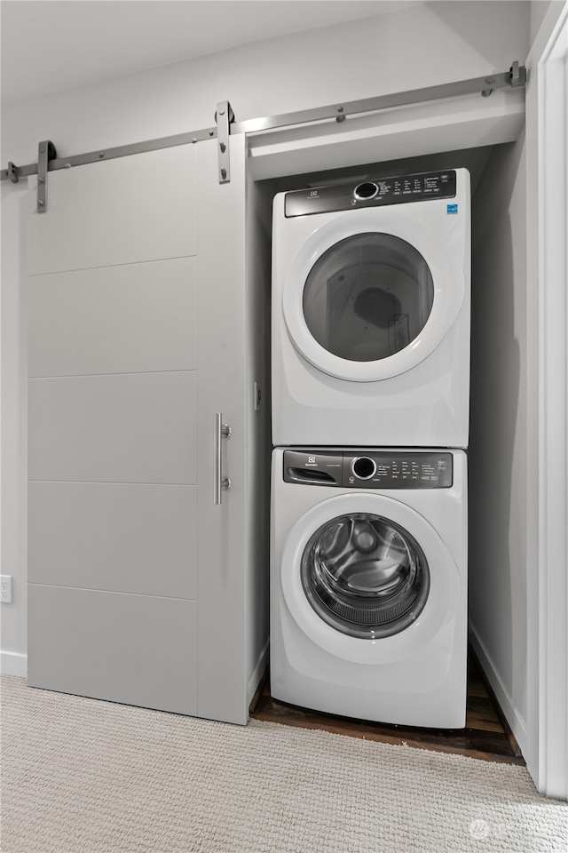 laundry room featuring a barn door and stacked washer and clothes dryer