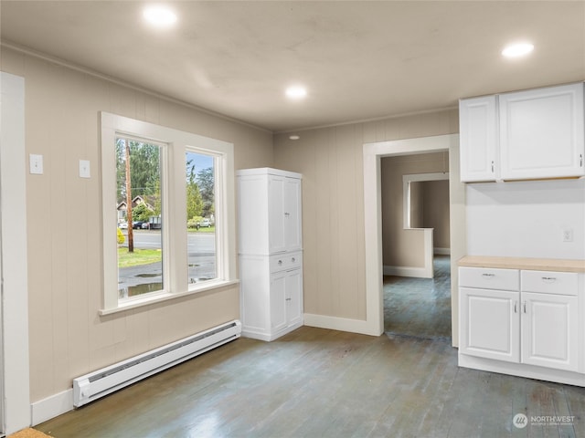 unfurnished dining area featuring dark wood-type flooring and a baseboard radiator