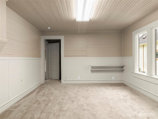 carpeted spare room with wood ceiling and wood walls