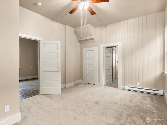 unfurnished bedroom with light colored carpet, ceiling fan, wood walls, and baseboard heating