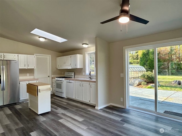 kitchen with stainless steel fridge, gas range gas stove, dark wood-type flooring, and white cabinets