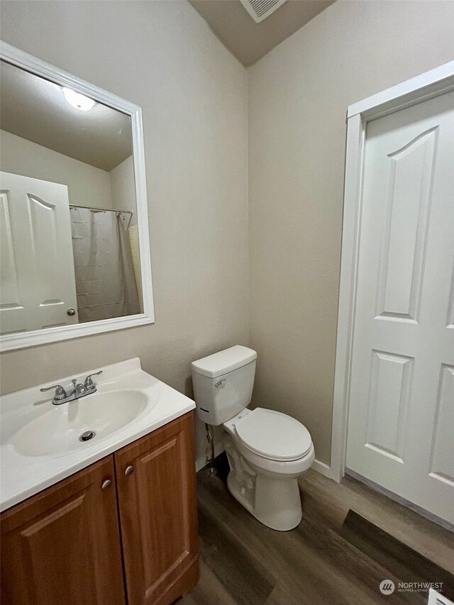 bathroom featuring walk in shower, hardwood / wood-style floors, vanity, and toilet