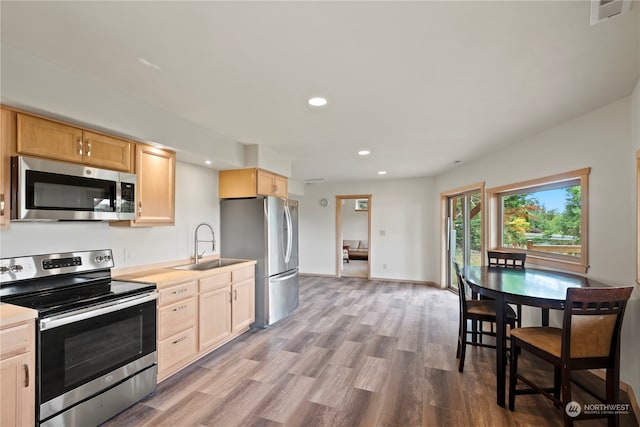 kitchen with light brown cabinetry, sink, light hardwood / wood-style flooring, and stainless steel appliances