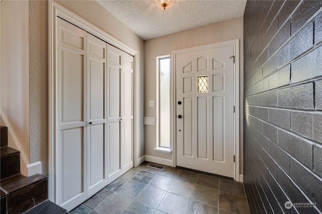 foyer with a textured ceiling and tile walls