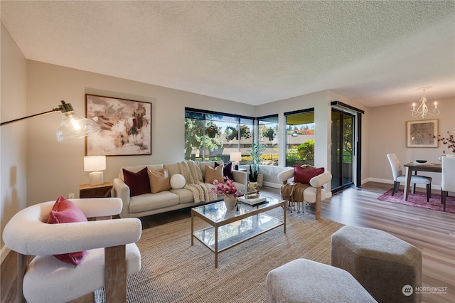 living room with an inviting chandelier, light hardwood / wood-style floors, and a textured ceiling