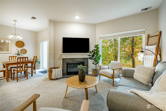 living room with a notable chandelier, a tiled fireplace, and carpet flooring