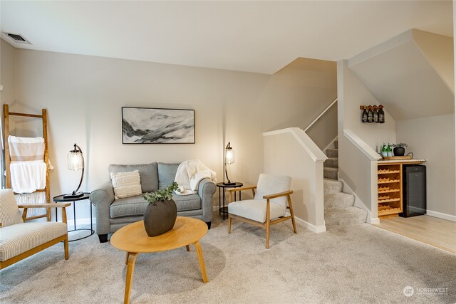 carpeted living room featuring bar and vaulted ceiling