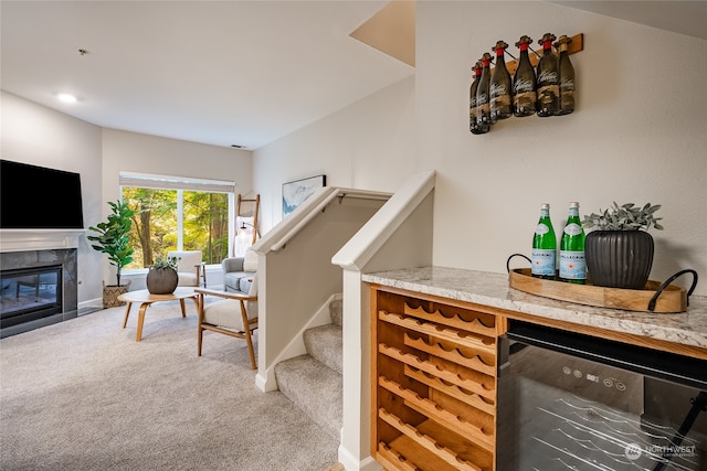 bar featuring beverage cooler, a fireplace, and carpet