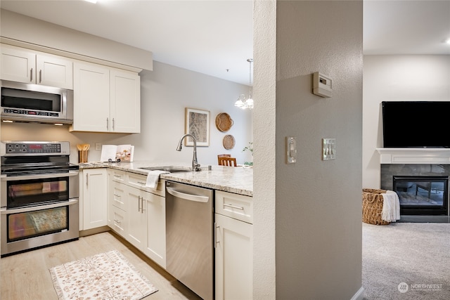 kitchen featuring sink, kitchen peninsula, stainless steel appliances, a tile fireplace, and light stone countertops