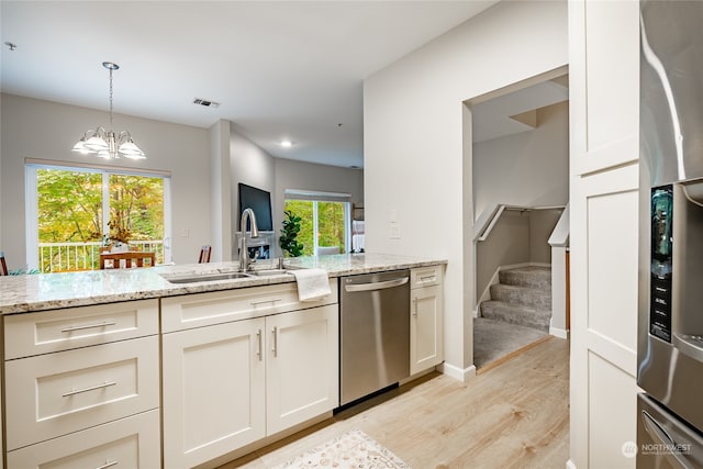 kitchen featuring light stone counters, stainless steel appliances, sink, light hardwood / wood-style floors, and a chandelier