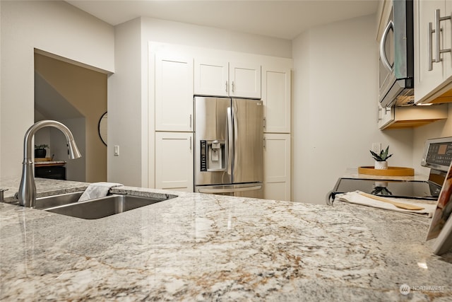 kitchen featuring light stone countertops, appliances with stainless steel finishes, sink, and white cabinetry